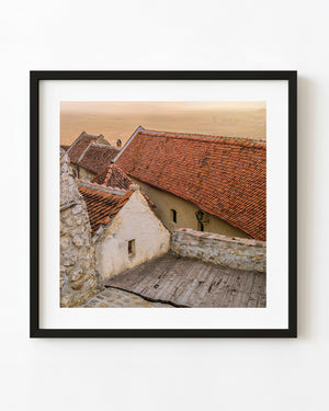Romanian terracotta roofs in warm evening light above pale stone walls