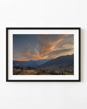 Golden sunset clouds above a forested Romanian valley and hillside fields