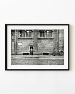 Rome street scene with a man in a doorway and a woman beside bicycles