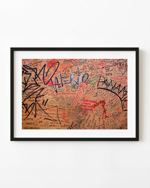 Handwritten graffiti covering warm orange plaster in Rome