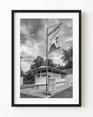 Route 66 streetcar diner beneath the tall Riviera Restaurant sign in monochrome