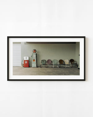 Two vintage Phillips 66 gas pumps beside a row of metal chairs