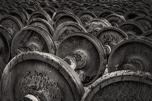 Monochrome photograph of repeated rail-car wheels and axles