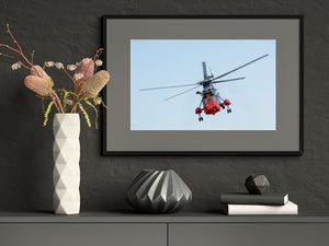 Royal Navy helicopter banking toward the camera beneath wide rotor blades