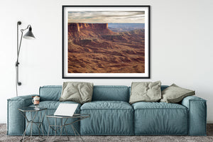 Vast canyon terrain with warm foreground rock and hazy distant plateaus