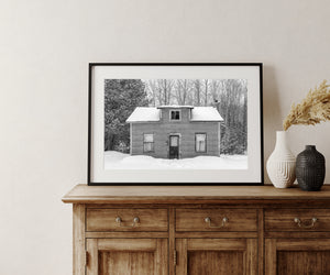 Rural house with a central dormer and chimney in a snowy woodland setting