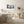 Falling snow outside a small house with peeling trim and curtained windows
