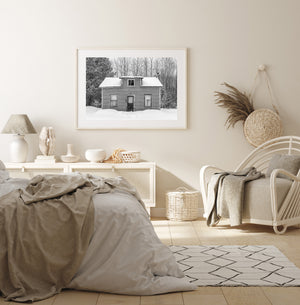 Falling snow outside a small house with peeling trim and curtained windows