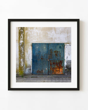 Rusted blue steel doors set into a weathered stadium wall