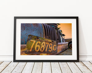 Rusted grille bars and peeling blue paint beneath a warm orange sky