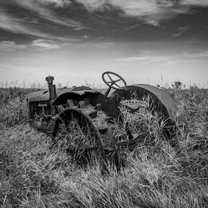 Rusting farm machinery surrounded by tall prairie grass