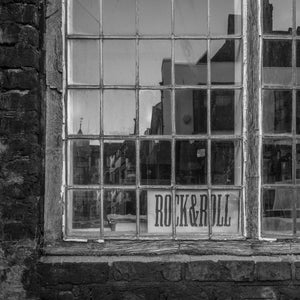 Rye bookstore window with a Rock and Roll sign and reflected street