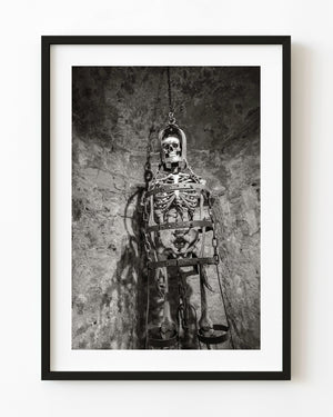 Suspended cage and skeleton display at Rye Castle in black and white