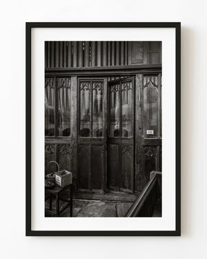 Carved church door beneath organ pipes in Rye in black and white