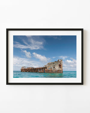 SS Sapona shipwreck in turquoise Bahamian water beneath a blue cloud-filled sky.