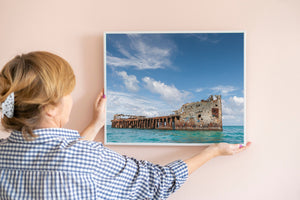 Rust-coloured shipwreck contrasts with turquoise Bahamian sea.