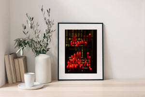 Colour still life of flickering candles behind dark iron bars