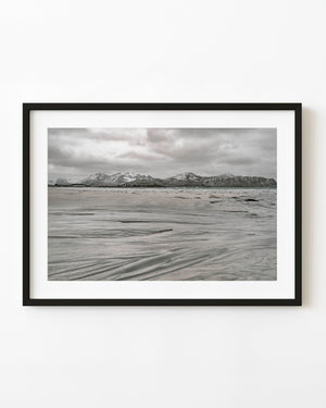 Flowing sand patterns on Sakrisoya beach beneath snowy mountains