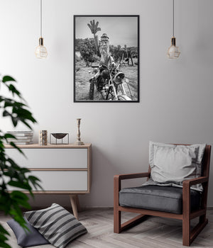 Monochrome folk art display with a bearded wooden figure and motorbike