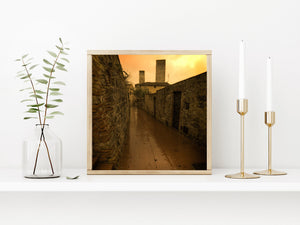 Empty winding lane between historic stone buildings in Tuscany