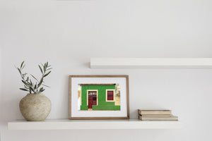 Red doorway beneath peeling trim on a green Santa Marta wall