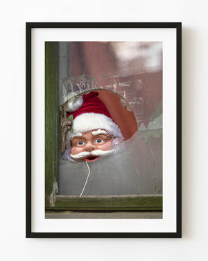 Santa figure seen through a broken Bucharest window