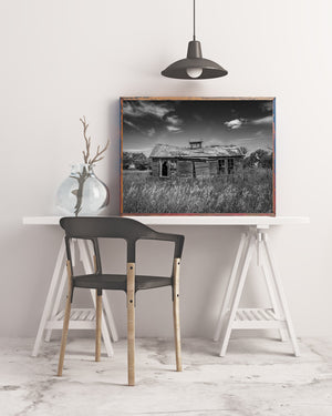 Monochrome prairie scene with an empty building surrounded by long grass