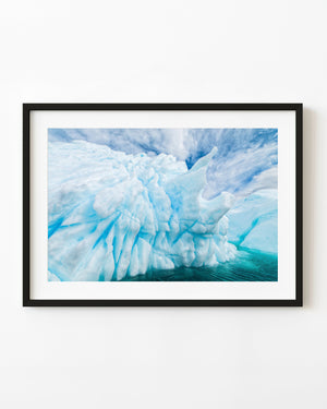 Sculptural blue Antarctic iceberg above turquoise water