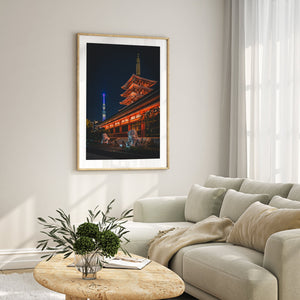Framed artwork of a cityscape with a pagoda on a wall above a beige sofa.