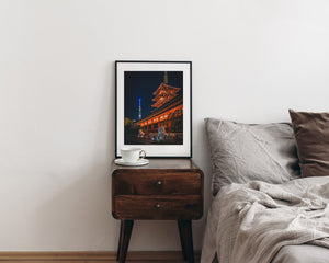 Framed photograph on a nightstand next to a bed with pillows and blankets.
