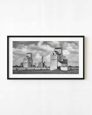 Shaunavon grain elevators beneath prairie clouds in black and white