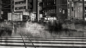 Motion-blurred pedestrians crossing striped wet pavement in Tokyo