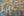 Large white scrawls over layered turquoise pink and yellow paint