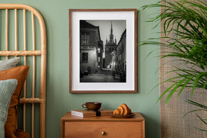 Black and white old-town scene with lantern light and a distant arched gateway