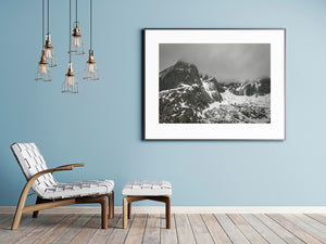 Low cloud draping jagged rock peaks streaked with winter snow