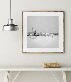 Snowmobiler passing houses beneath an overcast winter sky