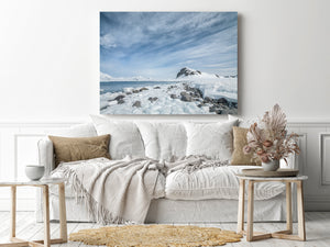 Dark shore rocks emerging through snow beneath an Antarctic mountain
