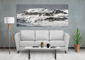 White ocean foam swirling around dark rocks edged with snow