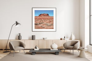 Sunlit sandstone butte rising above textured badlands