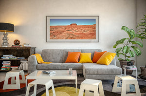 Red sandstone butte beyond sunlit badlands and dry desert ridges