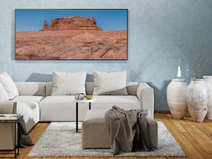 Red sandstone butte rising over sunlit pale badlands.