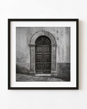 Black and white Spoleto wooden double door numbered 10 beneath a stone arch.