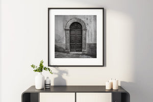 Weathered plaster surrounds a dark wooden door with two round knockers.