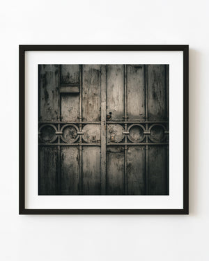Weathered Spoleto metal gate with circular ironwork, rivets and paired keyholes.