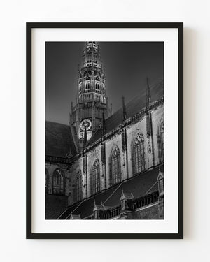 St Bavos Church clock tower above Gothic windows in Haarlem, photographed in black and white.