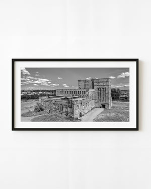 Black and white St Marys Paper Mill in Sault Ste Marie beneath scattered clouds.