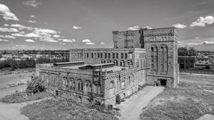 Historic stone paper mill with boarded arched windows and a tall square tower.