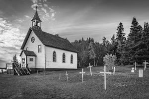 Small white wooden church with a bell tower and simple graveyard crosses.