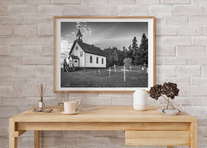 Wooden church beside forest trees and a quiet grassy burial ground.