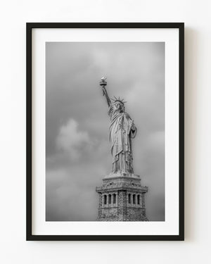 Statue of Liberty against soft grey clouds in black and white.